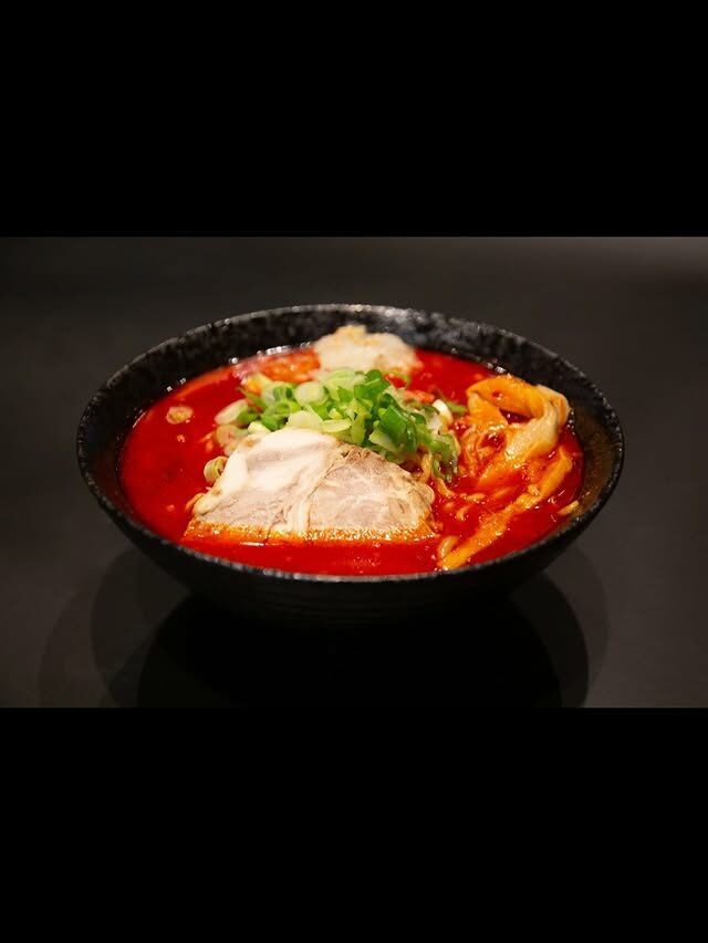 Spicy Sapporo red-miso ramen glowing on black